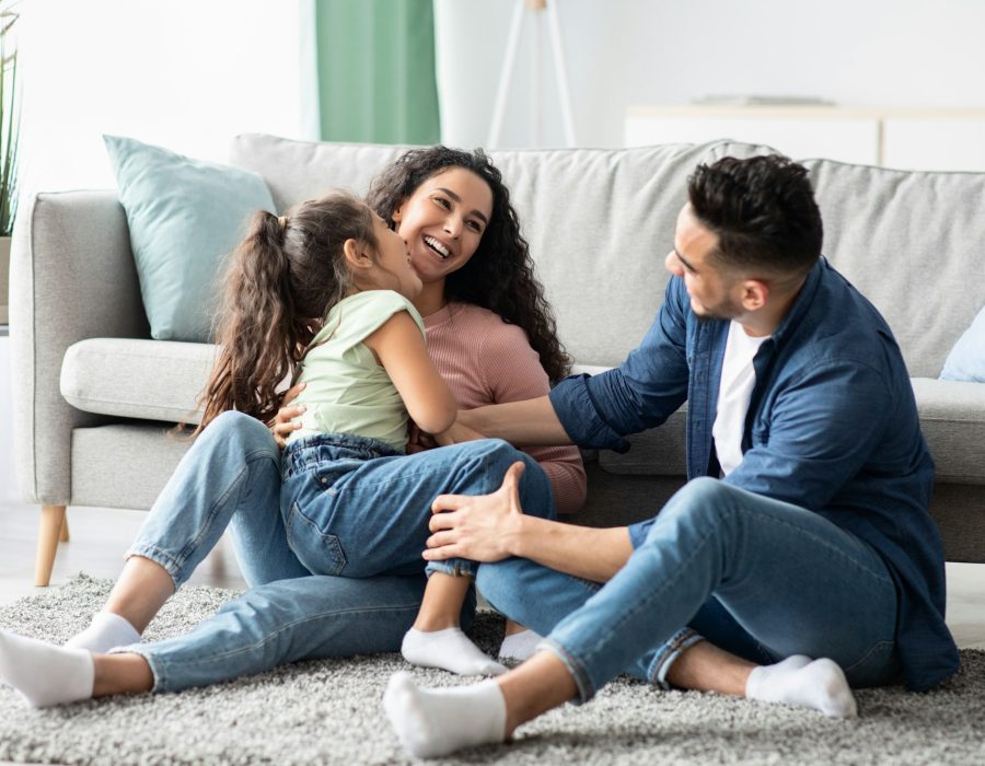Family Insurance Concept. Portrait Of Cheerful Young Parents And Their Little Daughter